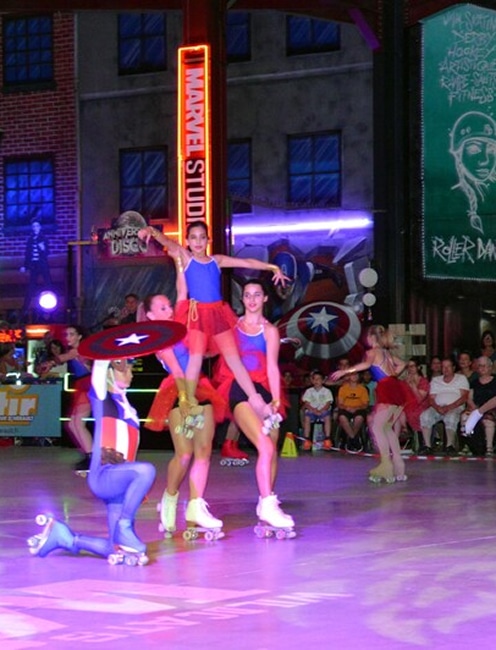 Patineurs Marvel Studios : Spectacle de roller artistique Spectacle de patinage artistique sur roulettes avec des danseuses costumées en super-héros, dont une en Captain America, devant un décor "MARVEL STUDIO".