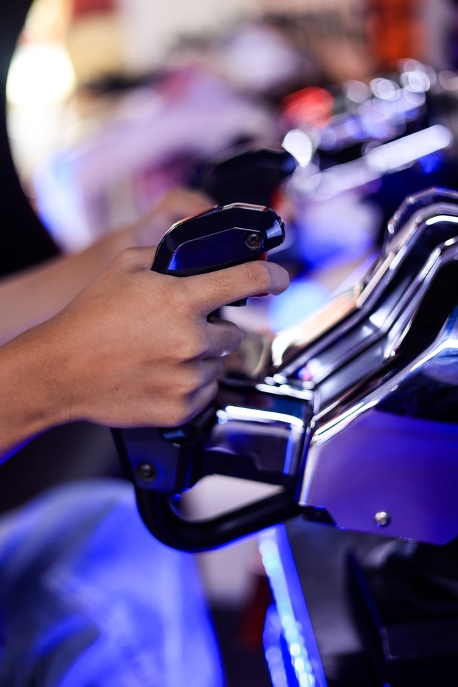 Joystick arcade : immersion et jeu sous lumière bleue Main tenant fermement un joystick de simulateur noir et chromé. La lumière bleue intense illumine l'appareil de jeu d'arcade.