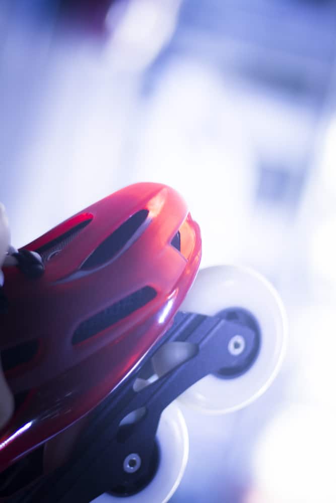 Rollerblade de sport rouge et noir : Prêt pour la vitesse Patin à roues alignées (rollerblade) rouge vif, coque ventilée, châssis noir et grandes roues blanches, éclairage froid.